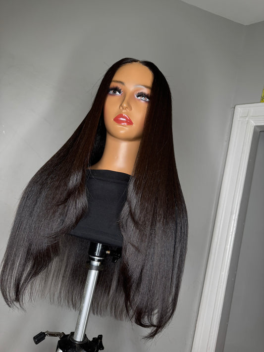 A mannequin head displaying a wig with long, straight, black hair, wearing a black top.