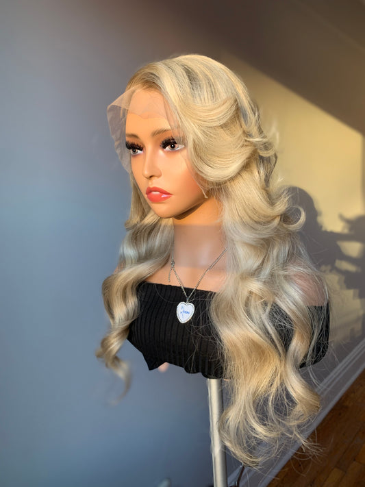 A wig stand displaying a smokey ash blonde frontal wig with a lace frontal.